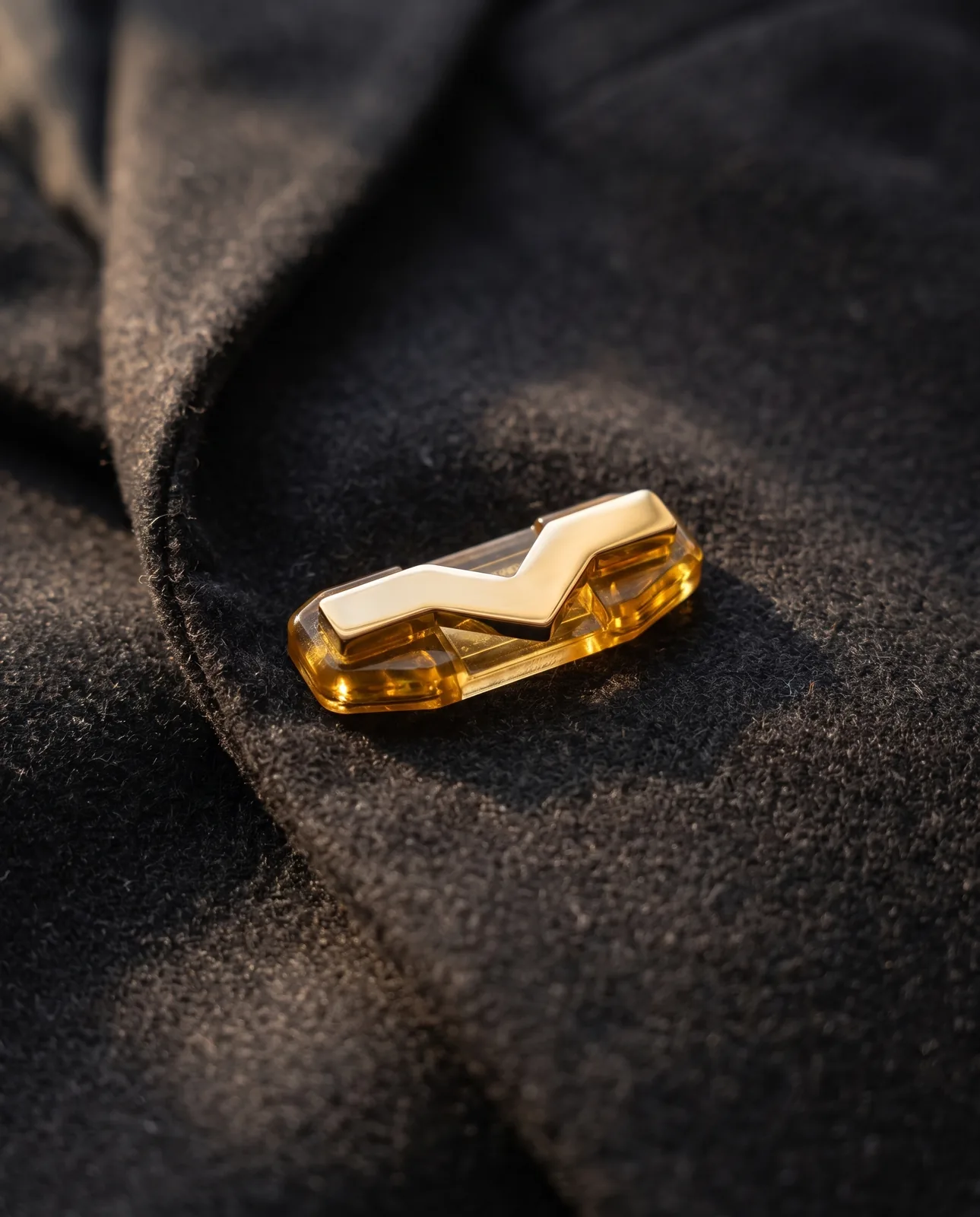 A gold StefMag on the lapel of a charcoal wool coat.
